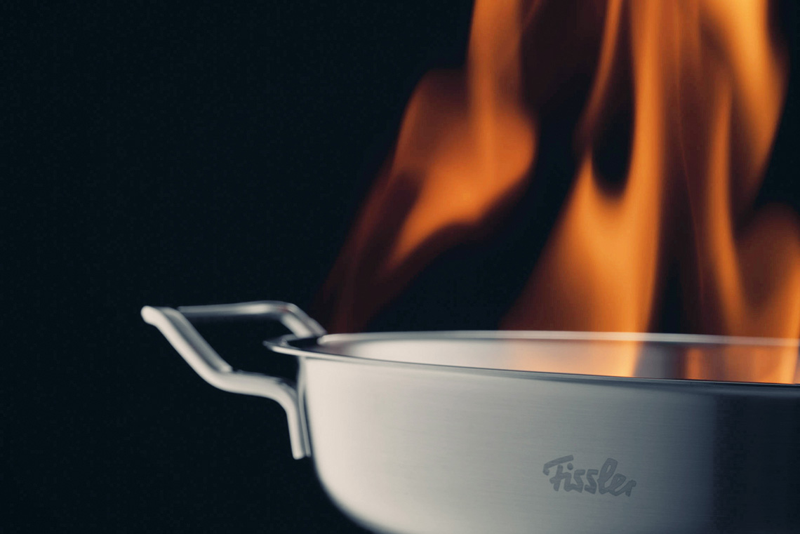 Stainless steel pan with flames on black background
